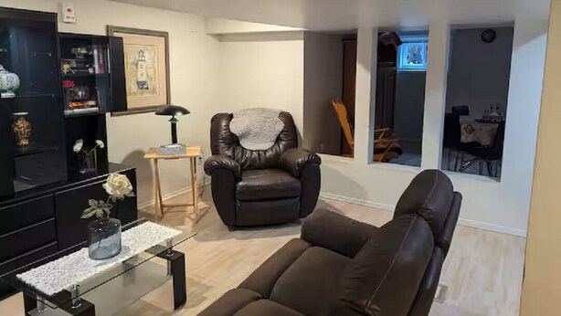 A living room with a leather sofa, a glass coffee table, and a black entertainment unit. - Espace tranquille et accueillante (Repentigny)