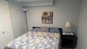 A bedroom with a bed, a nightstand, a lamp, and a wall painting. - Espace tranquille et accueillante (Repentigny)