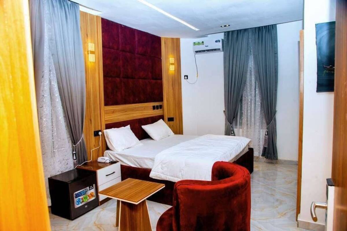 A hotel room with a bed, a small desk, a chair, and a wardrobe.