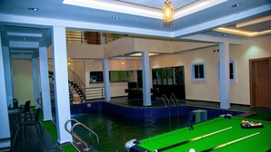 Une table de billard avec des billes, une table de billard et une table de billard dans une pièce avec un escalier et une vue sur la piscine.