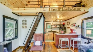 A cozy interior with a wooden staircase, a kitchen area, and a seating area with a rocking chair and a sofa.