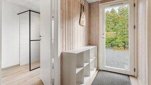 Een modern interieur met een houten wand, een witte bank en een deur naar een buitenruimte met bomen.