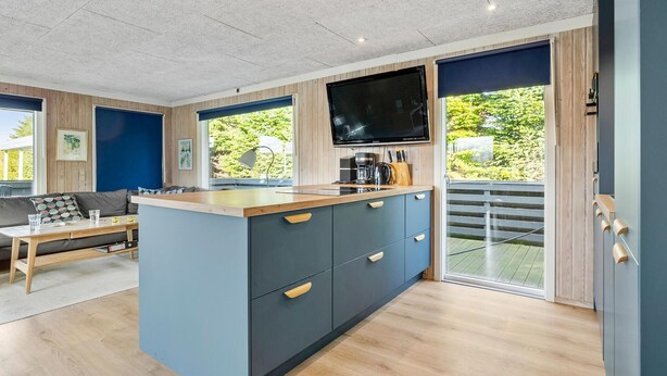 Een moderne keuken met een groot eiland, een flatscreen televisie en een schuifdeur naar een balkon.