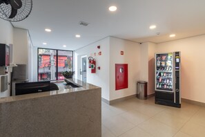 Eine moderne Lobby mit einer Rezeption, einem Verkaufsautomaten und einem an der Wand montierten Feuerlöscher.