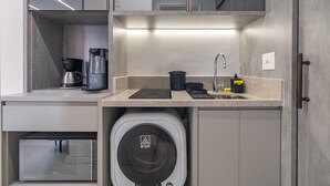 Eine kompakte Küchenzeile mit Mikrowelle, Kaffeemaschine und einer kompakten Waschetrockner-Kombination.