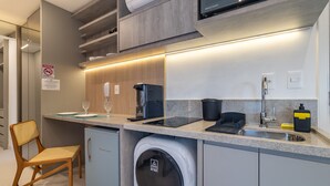 Une cuisine moderne équipée d’un lave-linge intégré, d’une machine à café et d’un évier.