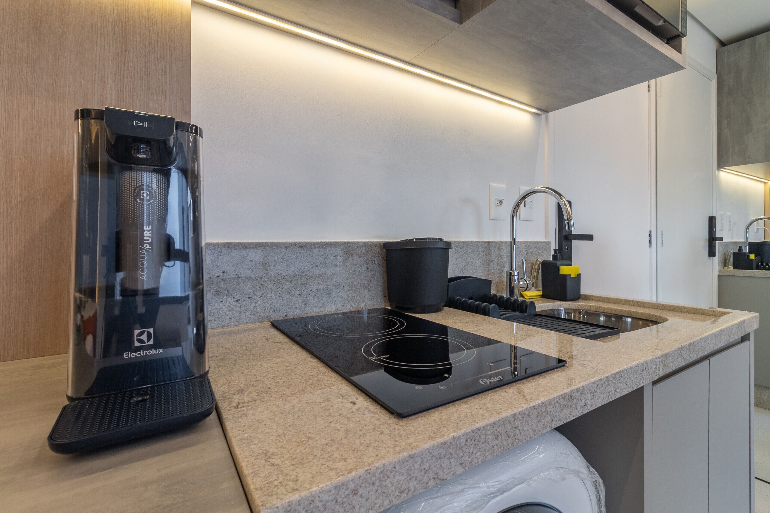 Eine moderne Küche mit Einbauherd, Spüle und Kaffeemaschine.