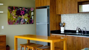A modern kitchen with wooden cabinets, a stainless steel refrigerator, and a black countertop. - Luxury condo with Rooftop pool & Ocean views (Boca de Tomatlán)