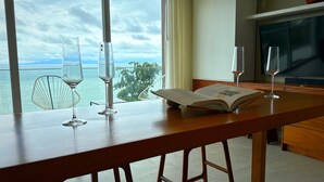 A wooden table with two wine glasses and an open book, overlooking a scenic view of the sea and mountains through large windows. - Luxury condo with Rooftop pool & Ocean views (Boca de Tomatlán)