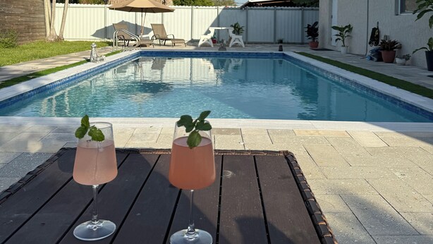 A swimming pool with two drinks on a table. - Modern Private Room -Super Clean and Quiet Stay (Miami)