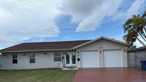 A single-story house with a garage, a well-maintained lawn, and a brick driveway. - Modern Private Room -Super Clean and Quiet Stay (Miami)
