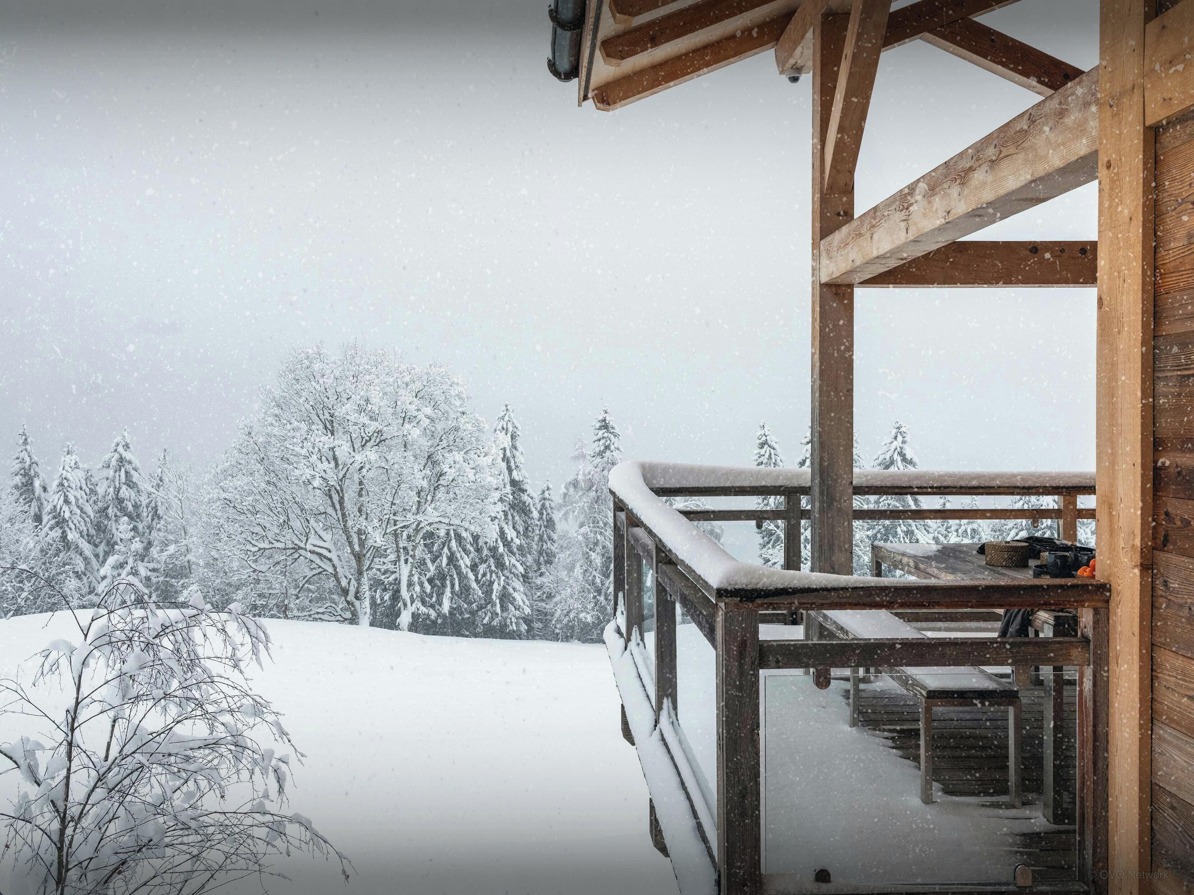 Un balcon en bois offrant une vue sur des arbres couverts de neige.