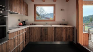 Eine moderne Küche mit Holzausstattung, einem eingebauten Backofen und einem großen Fenster mit Blick ins Freie.