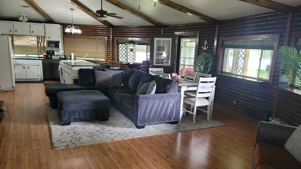 Ein gemütliches Blockhaus-Interieur mit einem Holzespeisetisch, einer Couch und einer Küchenzeile mit Mikrowelle und Schränken.