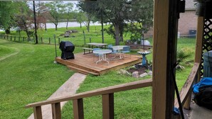 Ein Garten mit einer Holzterrasse, einem Grill und Gartenmöbeln.