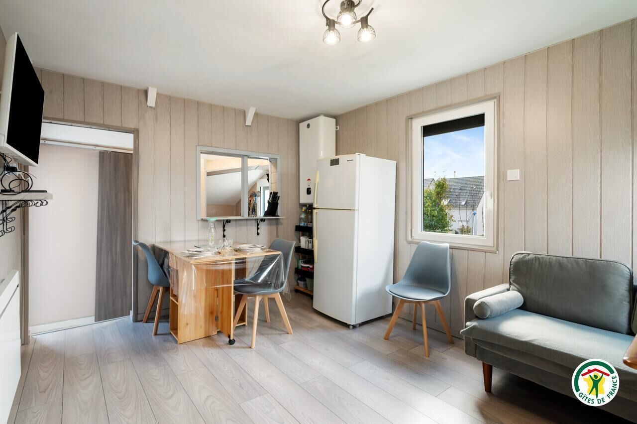 A modern kitchen with a dining table, chairs, a refrigerator, and a sofa.