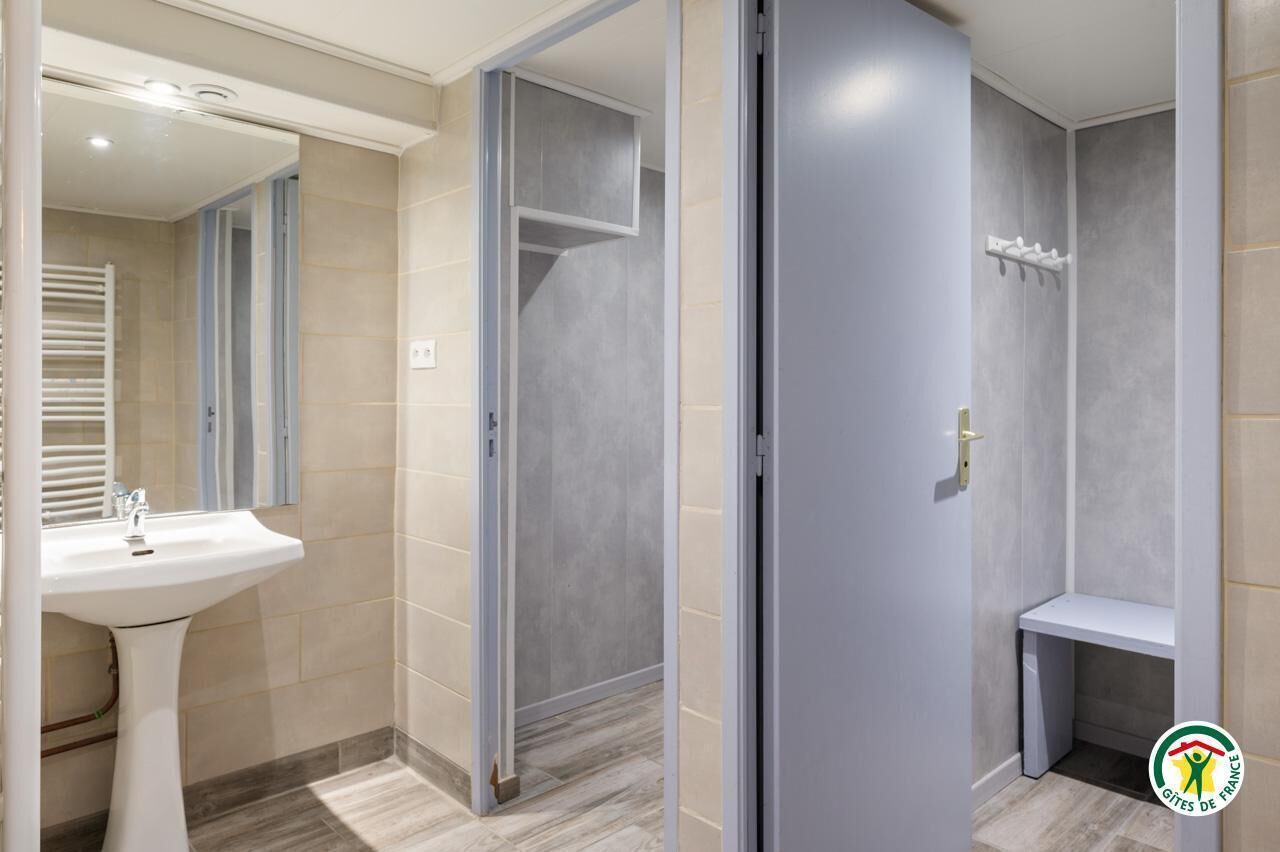 Une salle de bain moderne avec un lavabo sur colonne, un espace douche et un banc.