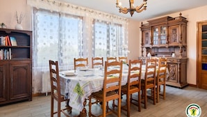 A dining room with a table set for six, wooden chairs, a chandelier, and a cabinet with glass doors. - Gîtes de France® - Villa des Champs (VILLERS SOUS FOUCARMONT)