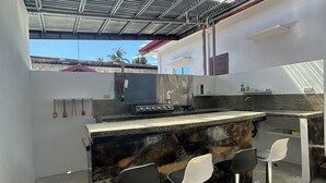 A modern kitchen with a marble countertop, four bar stools, and a gas stove.