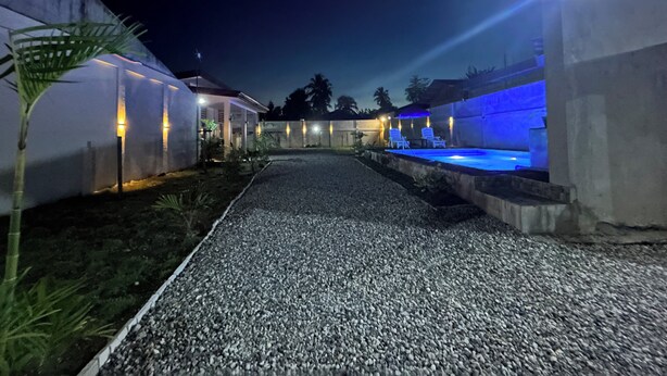 A pathway leading to a building with outdoor seating and illuminated walls.