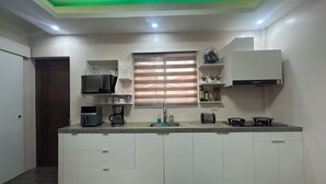 A modern kitchen with white cabinets, a microwave, a coffee maker, and a gas stove.