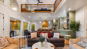 Un espacio habitable amplio con techo alto, comedor y cocina con armarios verdes.