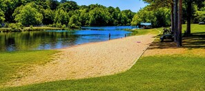 A lakeside park with a sandy beach, grassy areas, and a small structure in the background. - Cozy Retreat |  Pool Table, PingPong, Playset (Broken Bow)