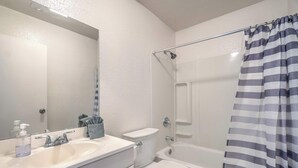 Un baño con lavamanos blanco, espejo, inodoro y bañera.