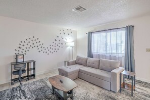 A modern living room with a sectional sofa, a small table, a desk, and a wall-mounted lamp. - Vegas Adventure Starts Here-Mins to Strip | Sleeps 6 (Las Vegas)