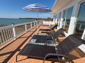 A deck with two lounge chairs and a striped umbrella, overlooking a body of water. - Chesapeake Bay Retreat (Cambridge)