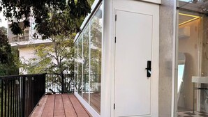 Una terraza de madera con puertas de vidrio que dan a una habitación.