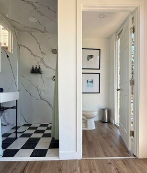 Un baño con inodoro, lavabo y zona de ducha con piso a cuadros.