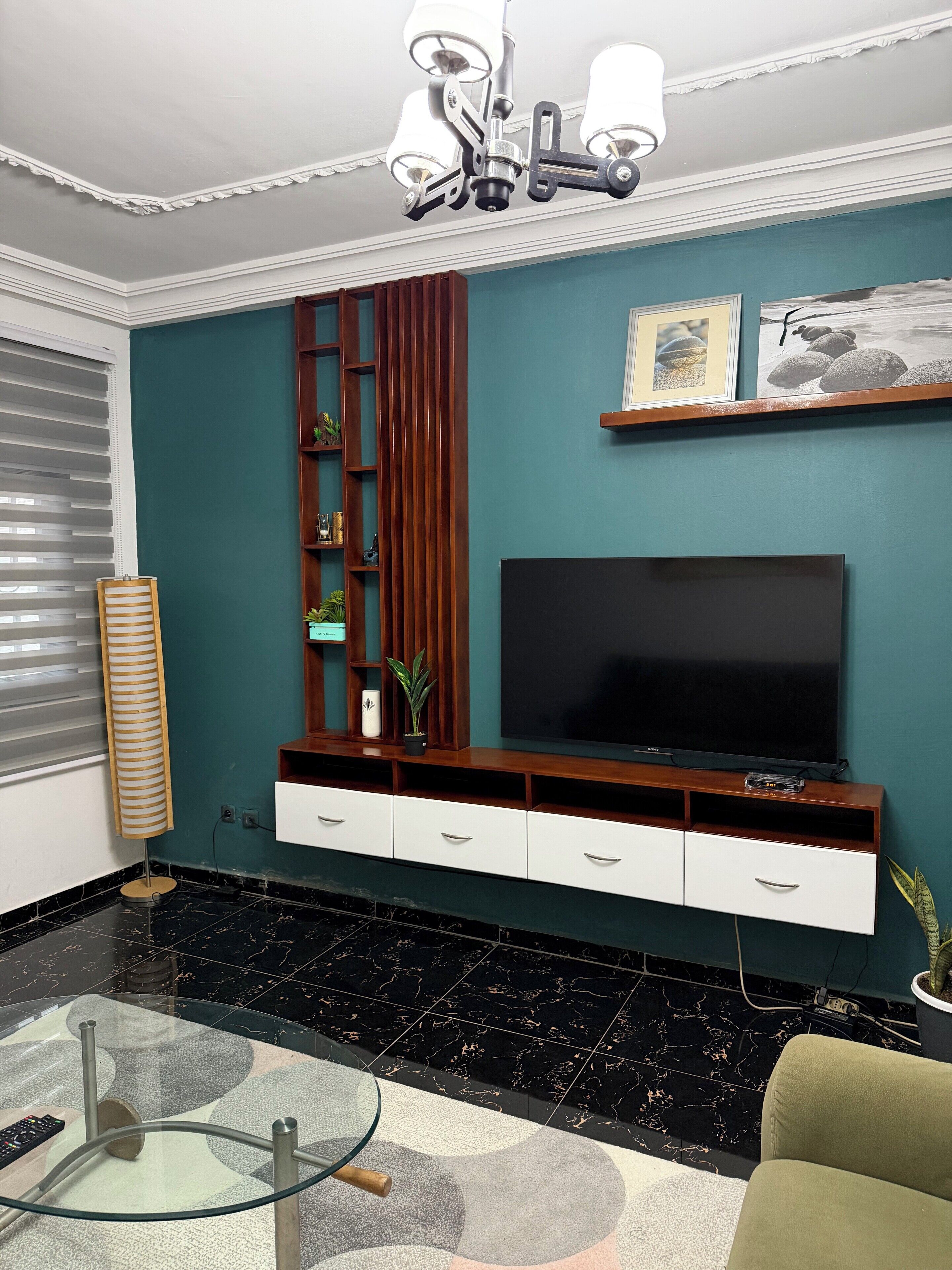 Un salon moderne avec un téléviseur à écran plat, un meuble de rangement en bois et une table basse en verre.
