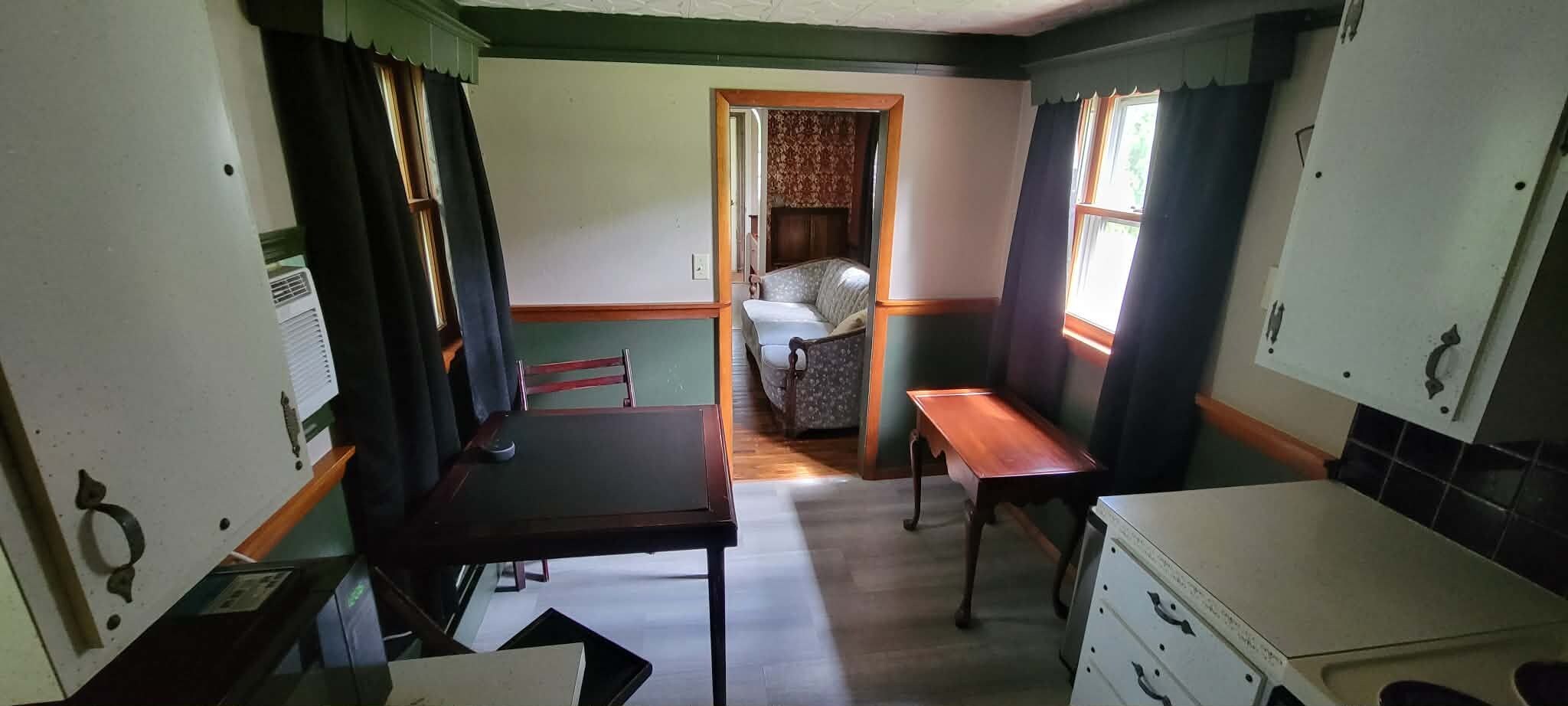 Une cuisine compacte comprenant une table à manger, un banc et un petit réfrigérateur.