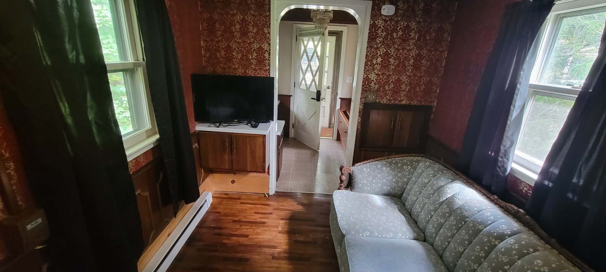 A compact living space with a sofa, a flat-screen TV, and a wooden cabinet.