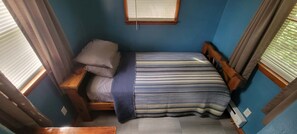 A small, single-bed room with a wooden headboard, a window with blinds, and a blue-striped bedspread. - Cute 1-bedroom tiny house with AC in charming Lewisburg (Lewisburg)