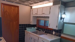 Une cuisine de taille réduite, équipée d’un évier, de placards et d’une fenêtre.