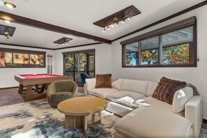Ein modernes Wohnzimmer mit Billardtisch, einer Couch und einem Couchtisch.