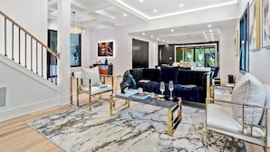 Ein modernes Wohnzimmer mit Treppe, einem dunkelblauen Sofa und einem Glastisch.