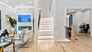 Ein modernes Interieur mit einer Treppe, einem Wohnbereich mit Sofa und Couchtisch sowie einem Essbereich mit einer Chandelier.