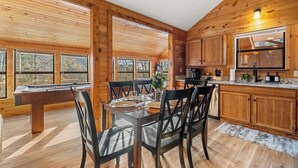 A wooden cabin interior with a dining table set for four, wooden cabinets, and large windows. - Hot tub, Sleeps 11, Near Dollywood, Pet-friendly (Sevierville)