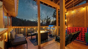 An outdoor deck with a fire pit, seating, and a view of the night sky. - Hot tub, Sleeps 11, Near Dollywood, Pet-friendly (Sevierville)