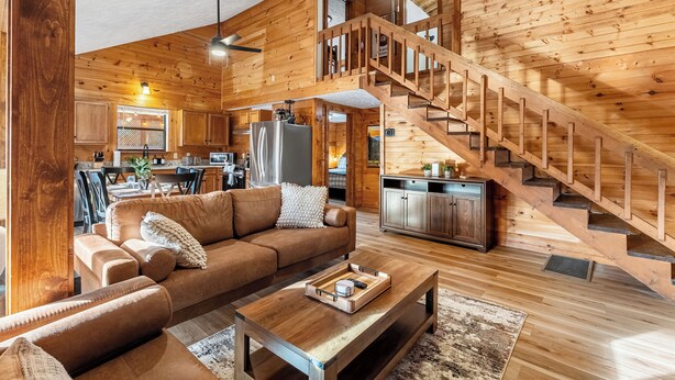A spacious living area with a wooden staircase, a sofa, and a coffee table. - Hot tub, Sleeps 11, Near Dollywood, Pet-friendly (Sevierville)