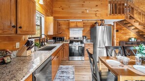 A wooden cabin interior with a kitchen, dining area, and staircase. - Hot tub, Sleeps 11, Near Dollywood, Pet-friendly (Sevierville)