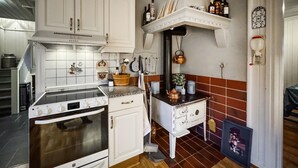 Keittiössä on valkoiset kaapit, liesi ja pesuallas. Työtasolla on erilaisia keittiövälineitä ja kahvinkeitin.