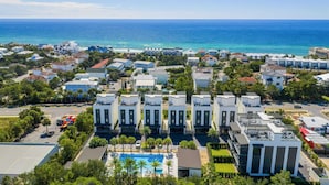 A coastal residential area with modern buildings, a swimming pool, and a view of the ocean. - Rooftop Deck w/ Gulf Views, Game Room Modern 30A by Avantstay (Santa Rosa Beach)