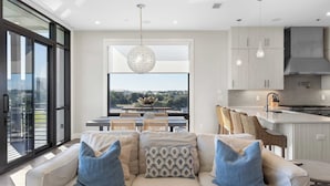 A modern living room with a sofa, dining area, and kitchen. - Rooftop Deck w/ Gulf Views, Game Room Modern 30A by Avantstay (Santa Rosa Beach)