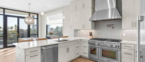 A modern kitchen with a central island, stainless steel appliances, and light wood cabinetry.