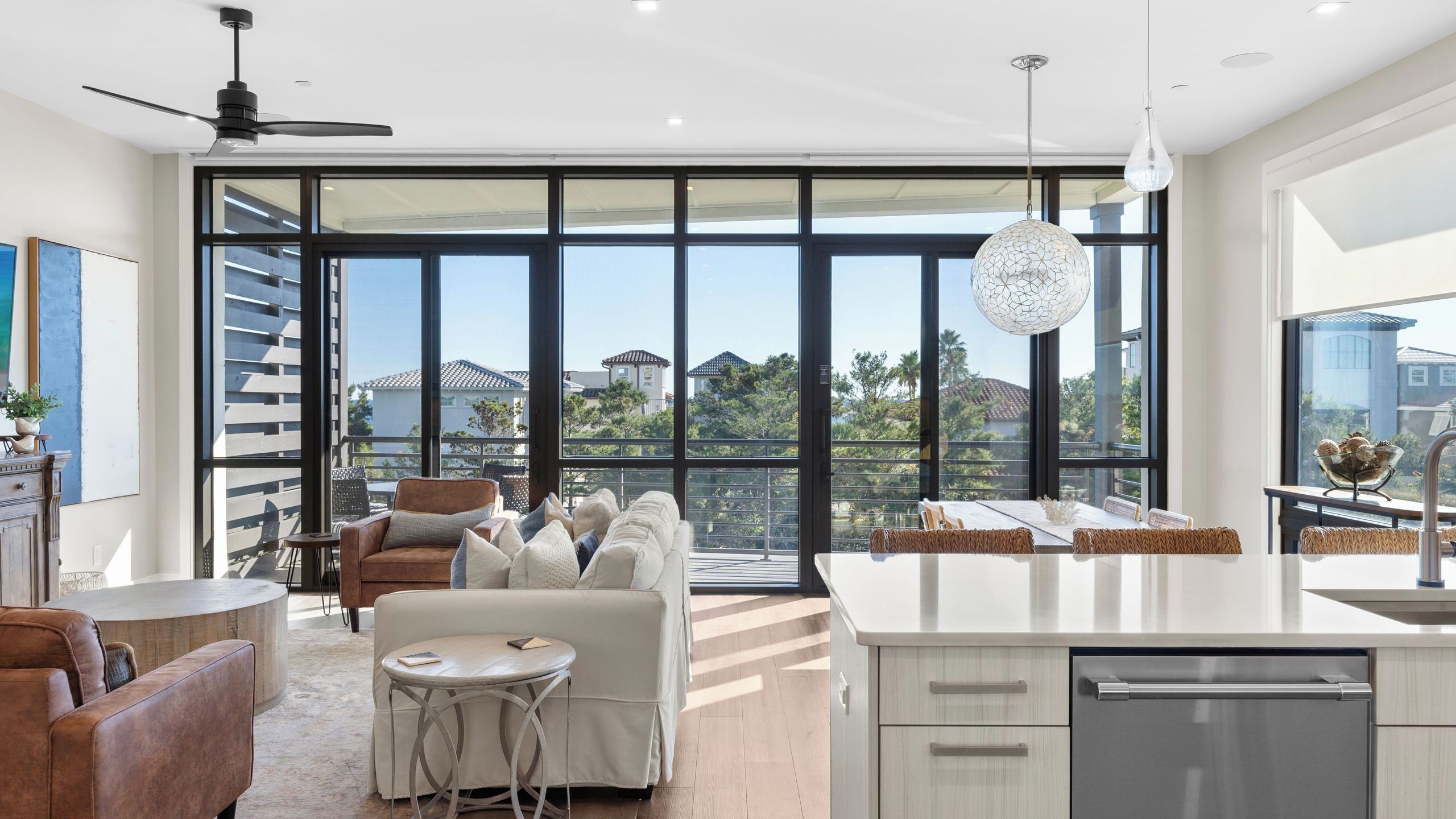 A modern kitchen with a large island, a dining area with a round table, and a seating area with a sofa and chairs.
