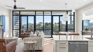 A modern kitchen with a large island, a dining area with a round table, and a seating area with a sofa and chairs. - Rooftop Deck w/ Gulf Views, Game Room Modern 30A by Avantstay (Santa Rosa Beach)